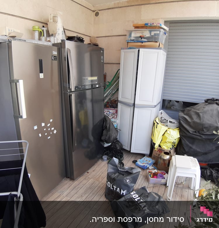 שני מקררים, ארון פלסטיק, קופסאות אחסון, שקיות על רצפת עץ